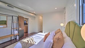 Une chambre moderne avec un lit, une armoire en bois, un miroir et une fenêtre.