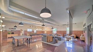 Un hall d’entrée spacieux avec une table de ping-pong, un coin salon et des conduits apparents.