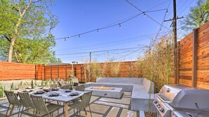 Une terrasse extérieure équipée d’une table à manger, de chaises, d’un foyer et d’un barbecue.