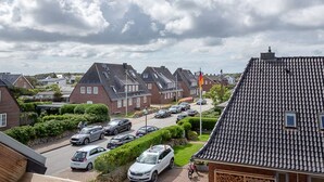 A residential area with houses, parked cars, and a flag. - Strand Brise - "Strand-Brise" vacation apartment in Westerland, in a prime location (Sylt)