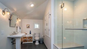 Ein modernes Badezimmer mit Waschbecken auf Säule, Toilette und einer Duschkabine.