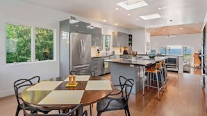A modern kitchen with a central island, stainless steel appliances, and a view of the sea.