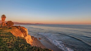 A coastal landscape with a cliff, beach, and ocean.