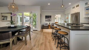 Une cuisine moderne dotée d’un îlot central, de tabourets de bar et d’un coin repas avec une table ronde et des chaises.