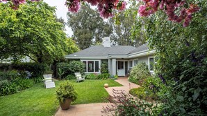 Une maison dotée d’une pelouse bien entretenue, d’un patio et d’un jardin où poussent diverses plantes et fleurs.