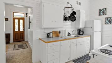 A kitchen with white cabinets, a wooden countertop, a stove, and hanging pots.