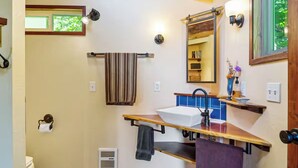 A bathroom with a sink, mirror, towel rack, and a window with greenery outside.