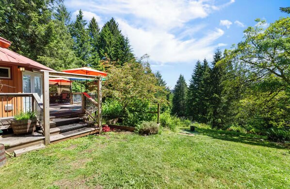 A wooden house with a porch, outdoor seating, and a garden. - Hillside Deck Cottages: A cozy, rustic PNW retreat perfect for 4. (Junction City)