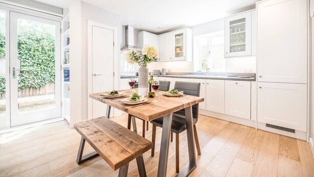 A modern kitchen with white cabinets, a wooden dining table, and a bench. - Skimming Stones, Southwold (Suffolk)