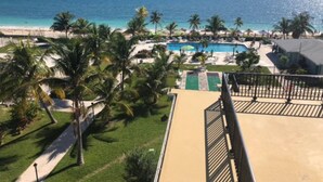A resort with a pool, palm trees, and a beach view.