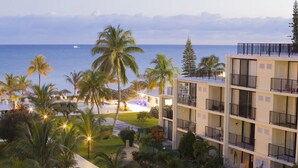 A hotel with multiple floors, outdoor seating, and a view of the ocean.