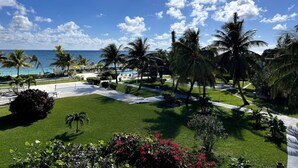 A resort with a pool, palm trees, and a view of the ocean.