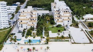 A beachfront hotel with multiple buildings, a pool area, and a sandy beach.