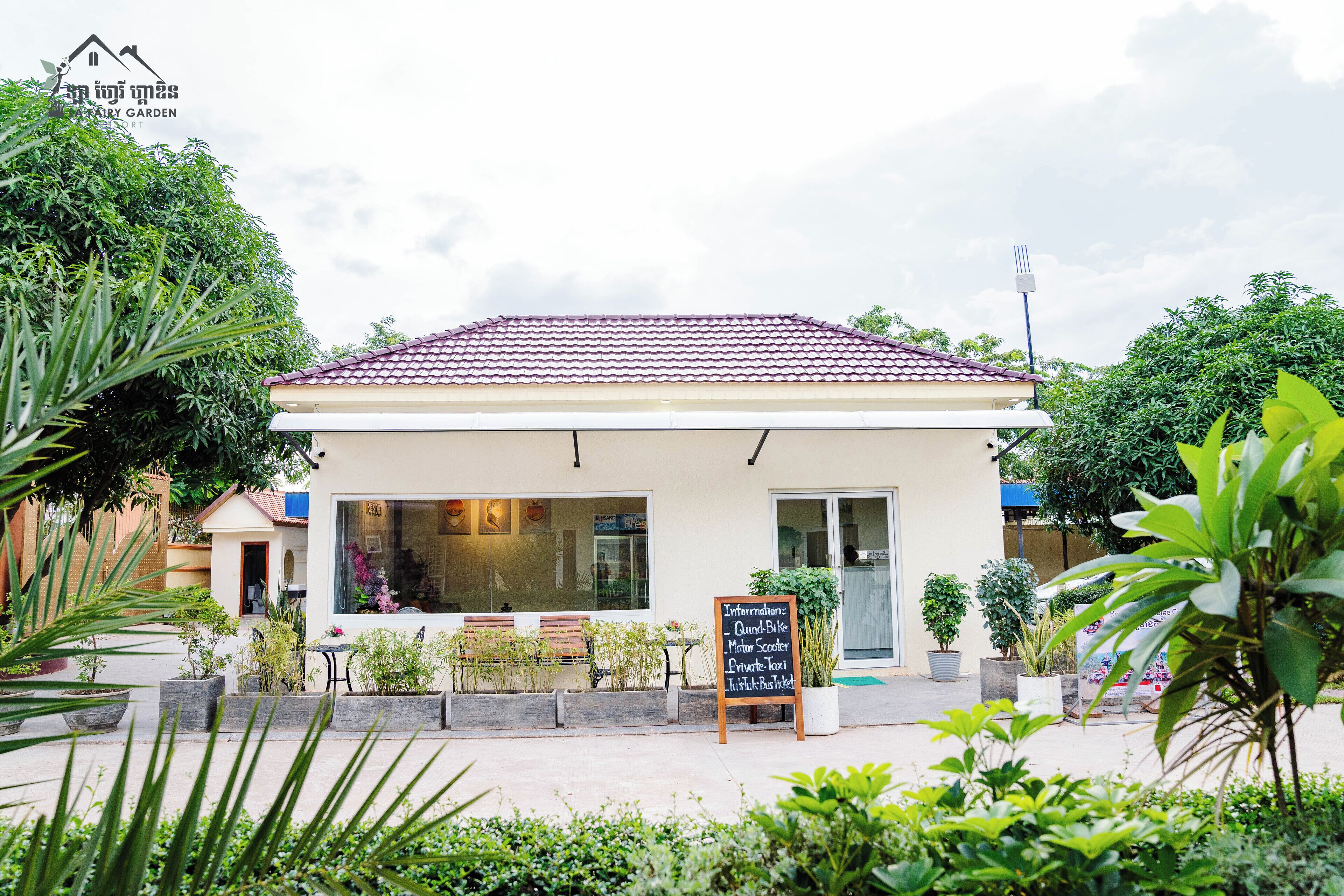 A small building with a tiled roof, surrounded by potted plants and greenery.