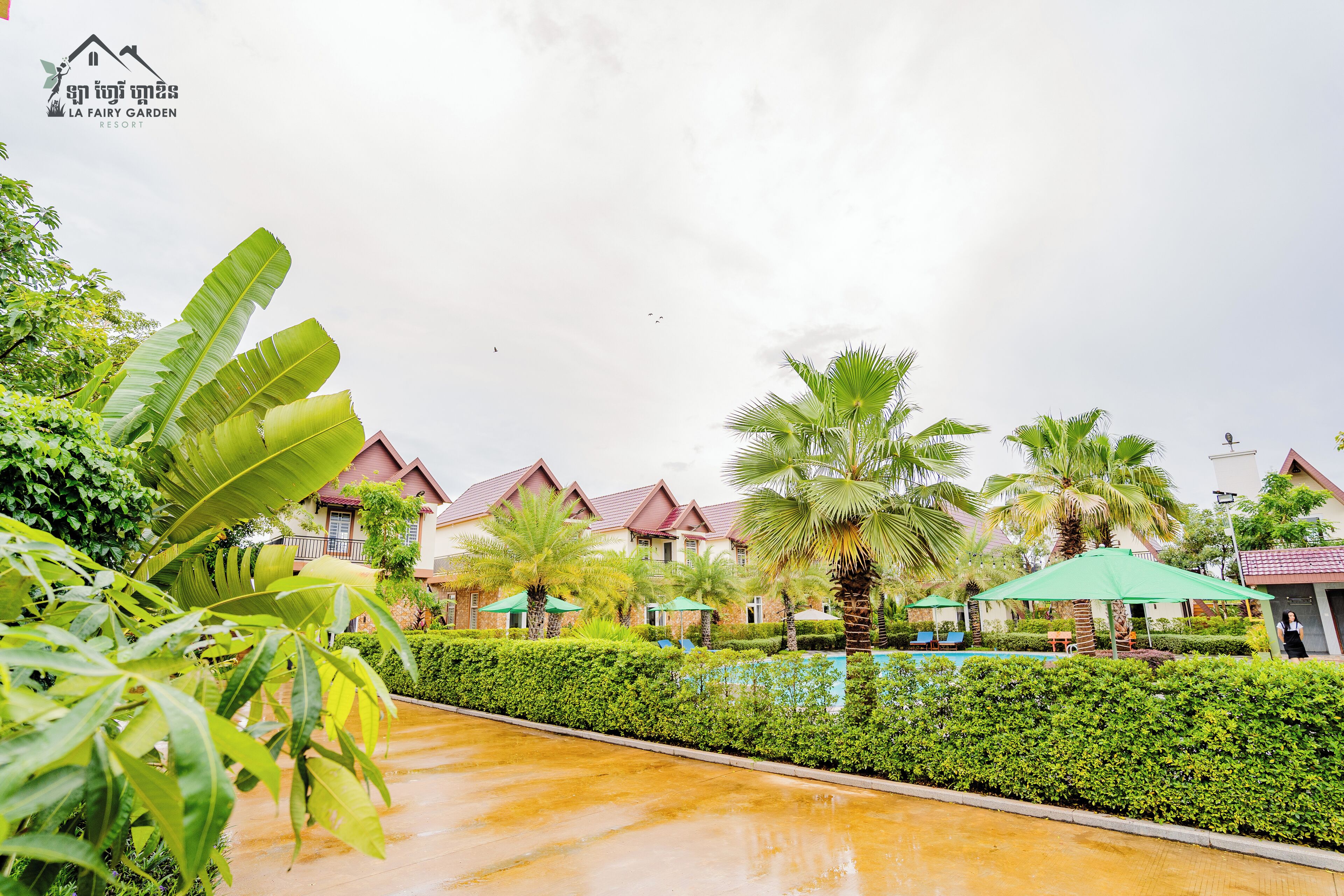 A resort with multiple buildings, a swimming pool, and lush greenery.