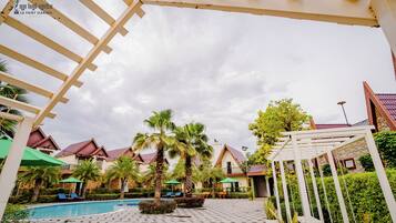 A pool area with palm trees, lounge chairs, and a pergola structure.