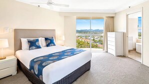 Ein Hotelzimmer mit einem großen Bett, einem Deckenventilator, Blick auf die Stadt und einem Kleiderschrank.