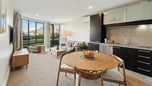 A modern living room with a dining table, sofa, and kitchen area. - The Beacon - Town Centre Apartment 620 (Queenstown)