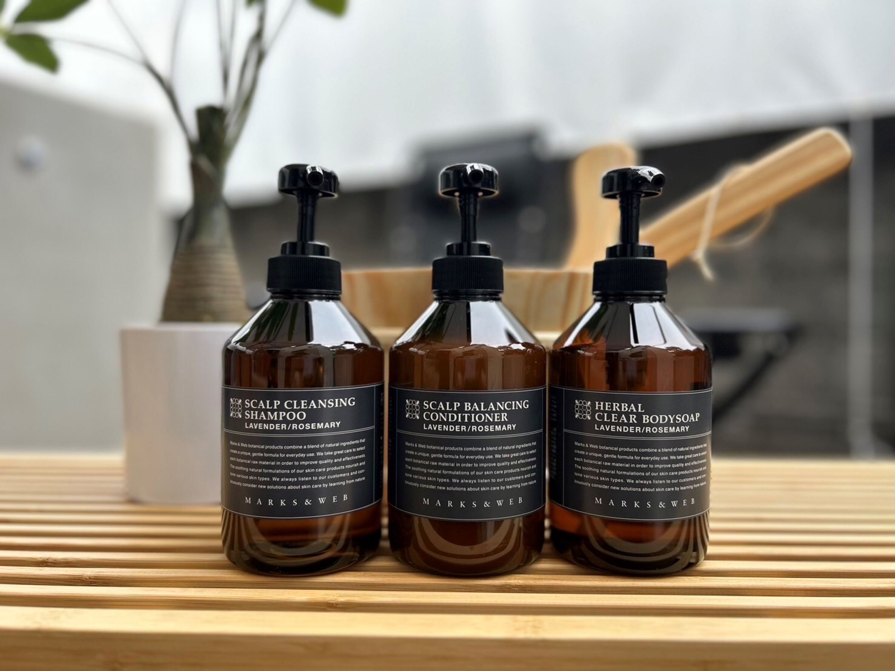 Three bottles of Marks & Web skincare products on a wooden surface.