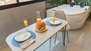 A breakfast setup with croissants, orange juice, and a hot tub in the background. - Cozy Aparta-Suite Studio | Jacuzzi | Rosa Negra (Medellín)