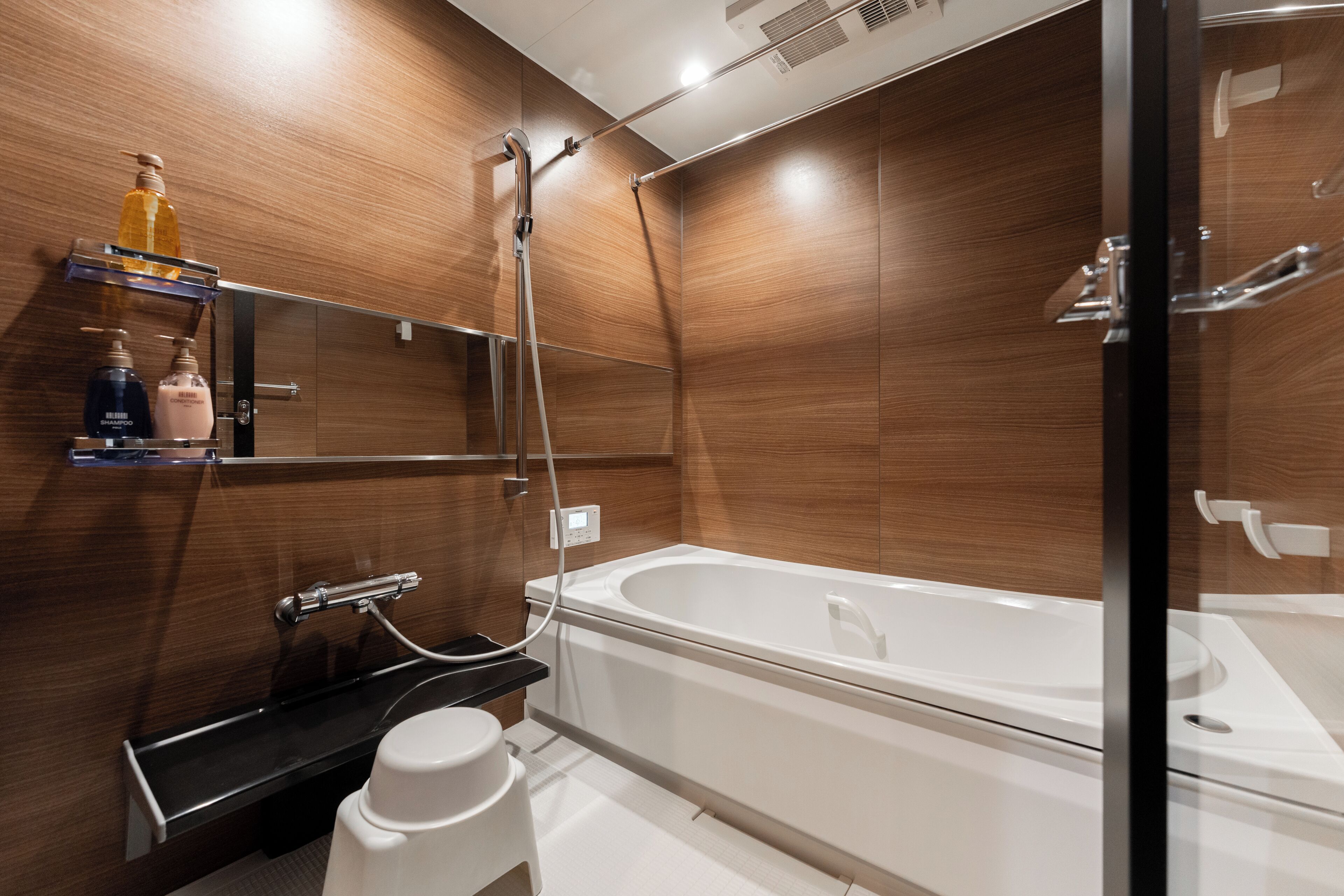Een moderne badkamer met een douchecabine van glas, een witte badkuip en houten lambrisering.
