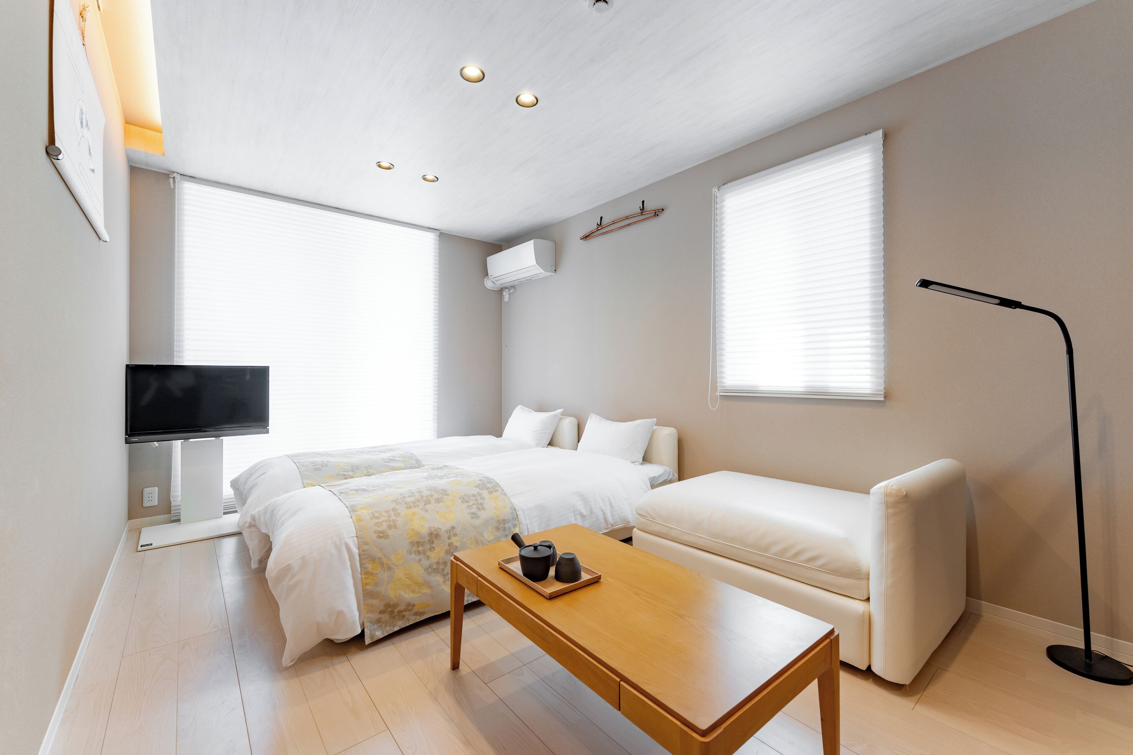A modern bedroom with a bed, a sofa, a coffee table, a TV, and a floor lamp.