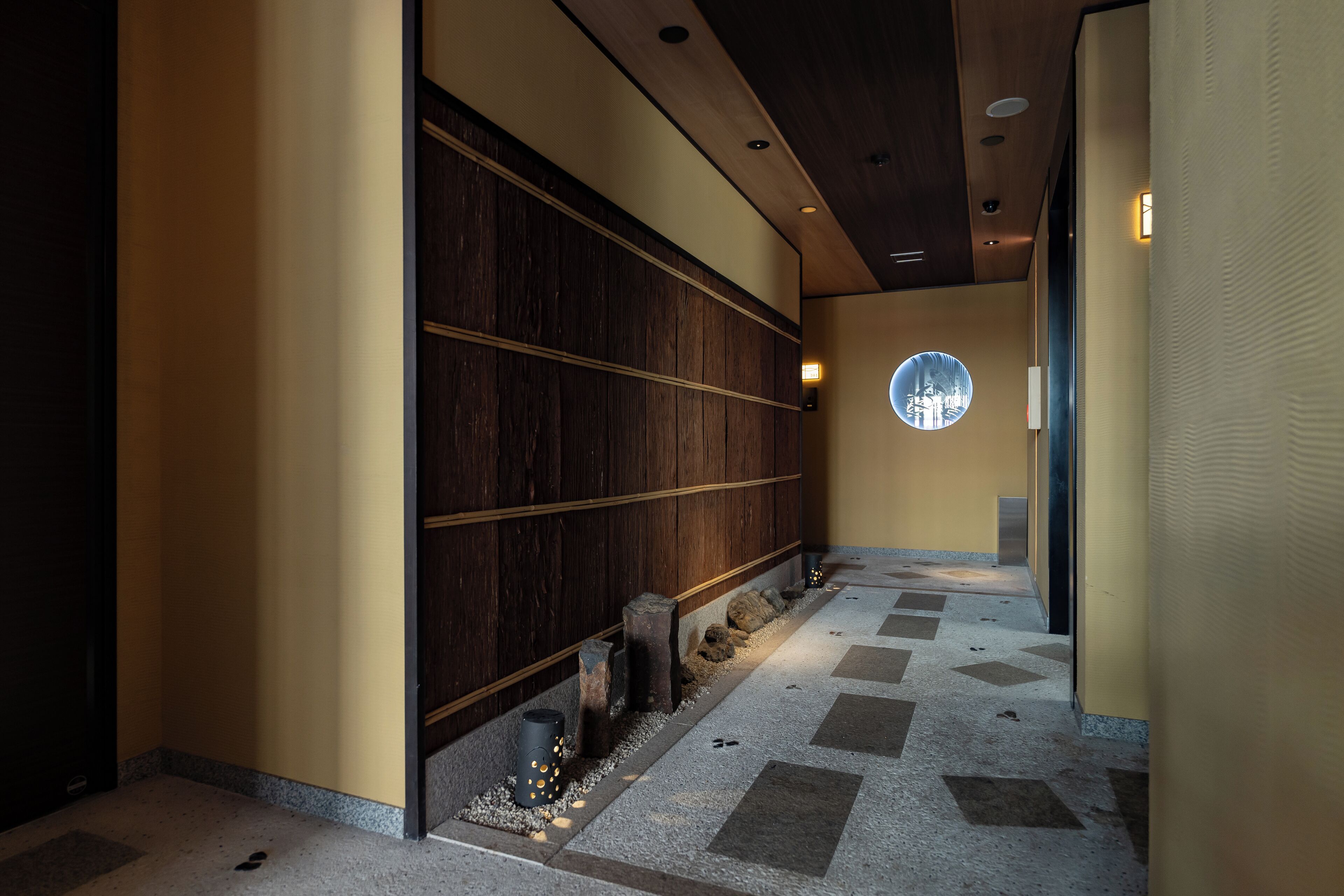 Un couloir avec un mur en bois, une fenêtre ronde et un sol à motifs.