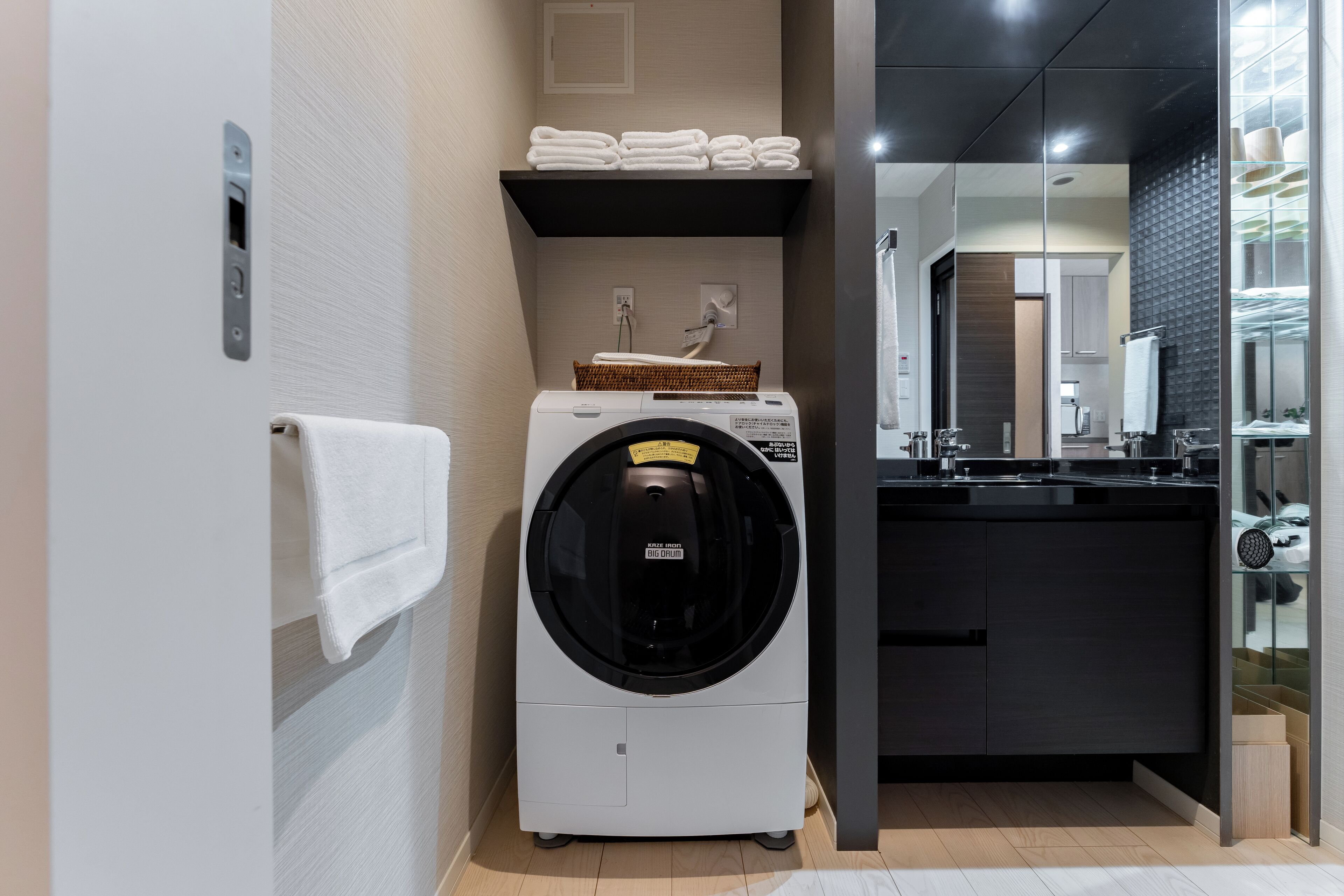A compact, modern bathroom with a built-in washer and dryer, a towel rack, and a mirror.