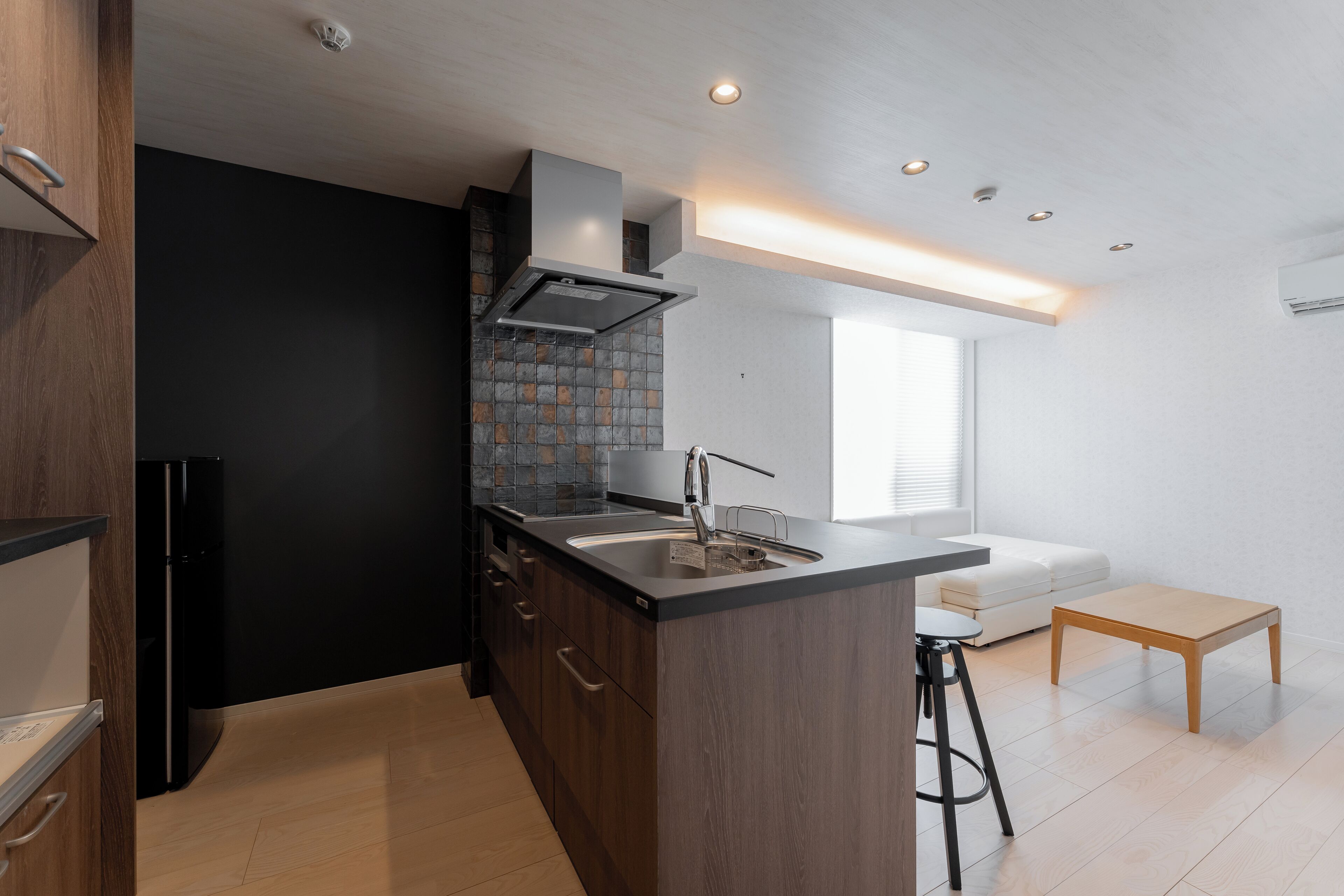 A modern kitchen with a central island, dark cabinetry, and a black refrigerator.