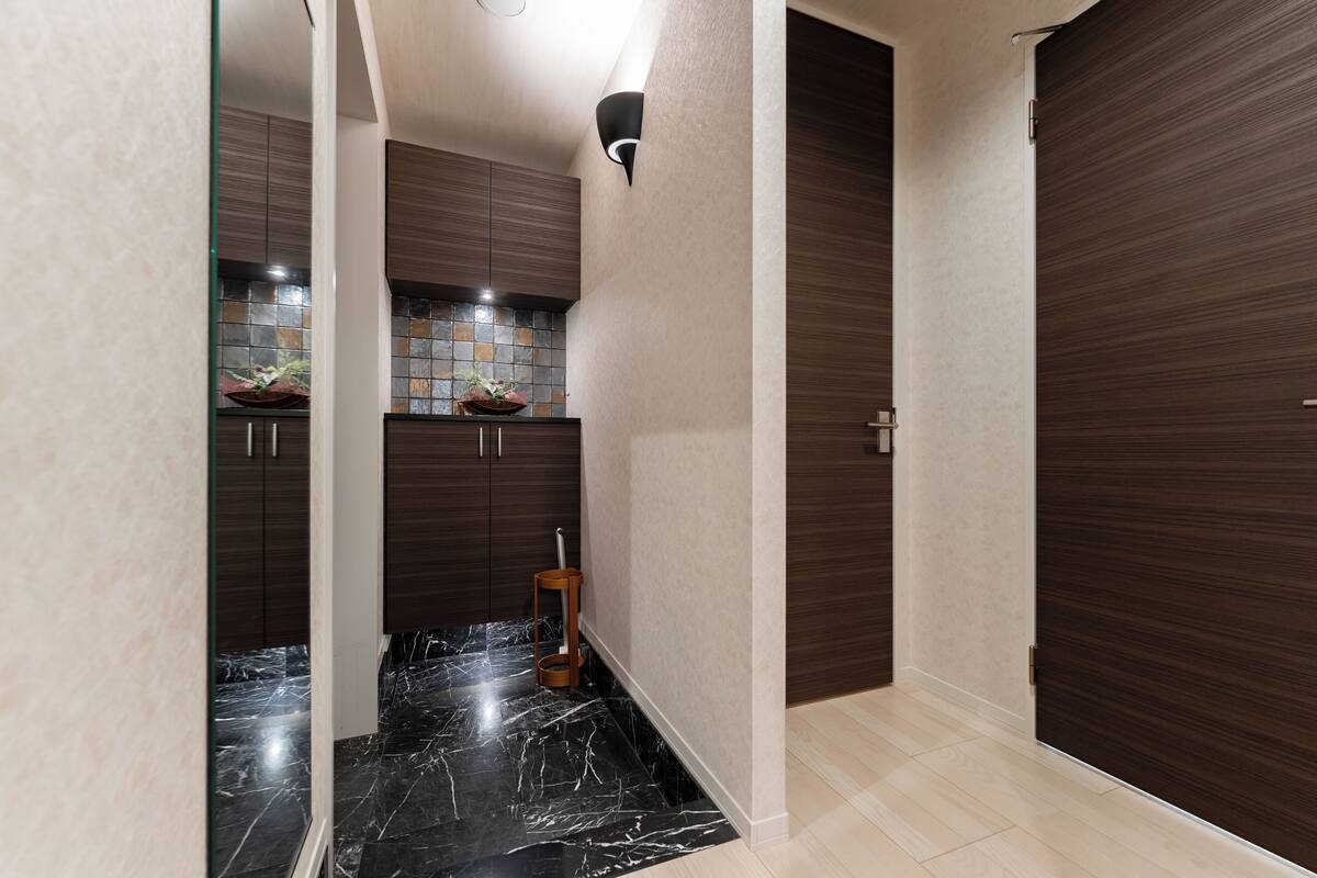 A modern hallway with dark wooden cabinets, a tiled backsplash, and a marble floor.