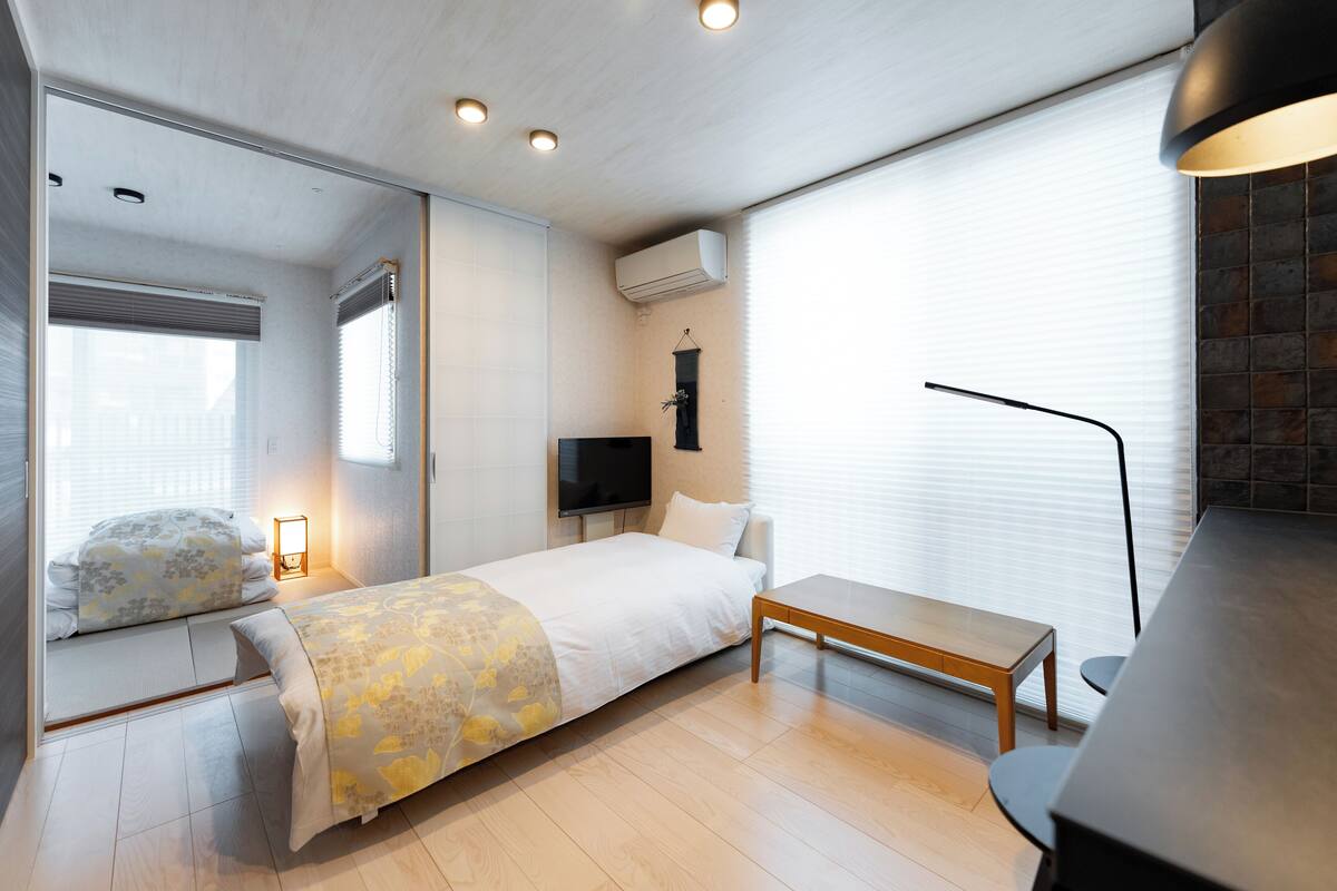 A modern bedroom with a bed, bedside table, and a TV.