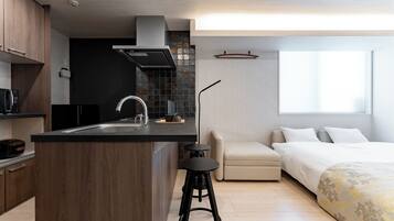 A modern kitchen with a central island, a built-in stove, and a black countertop. There is a small stool in front of the island.