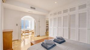 A bedroom with a bed, a wardrobe, a desk, and a view through an arched doorway. - Villa 'Casa Naranjita' with Sea View, Wi-Fi and Heated Pool (Salobreña)