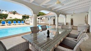 Un'area esterna coperta con piscina, lettini e un tavolo in vetro con sedie.