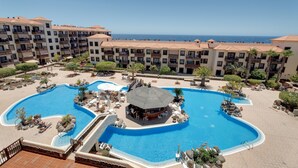 Un complexe hôtelier doté d’une grande piscine, de nombreux balcons et offrant une vue sur la mer.