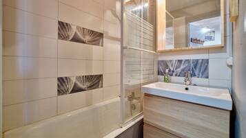 Une salle de bain moderne avec une baignoire, une douche à parois de verre et un meuble-lavabo avec un miroir.