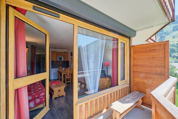 Une pièce aux murs en bois, avec un banc, une table et une vue sur la cuisine et la salle à manger.