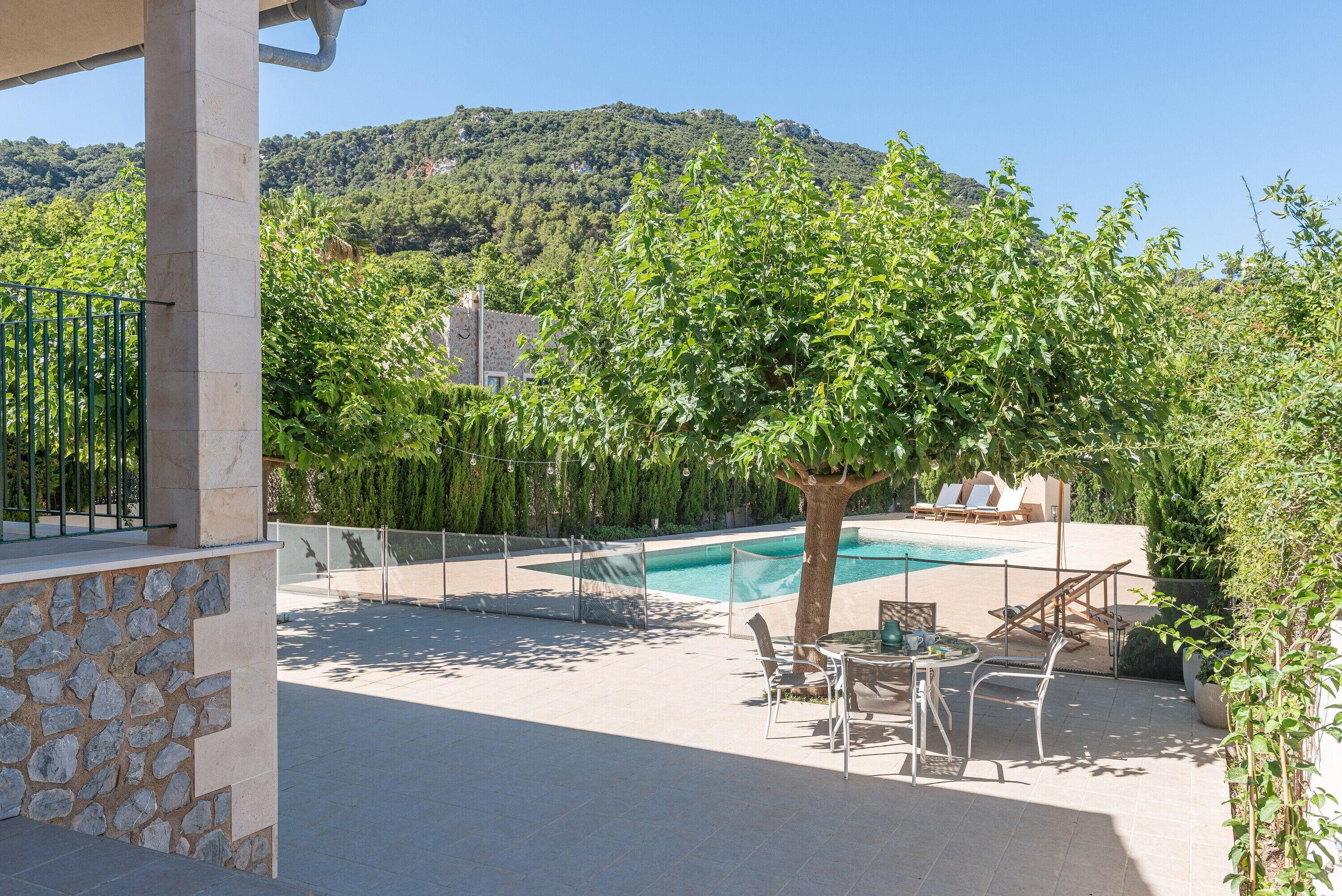 Un espace piscine agrémenté d’un mur en pierre, d’un arbre et offrant une vue sur une montagne.