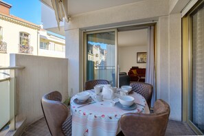 Een balkon met een eettafel, stoelen en een schuifdeur naar een binnenruimte.