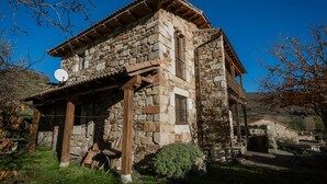 Un edifici de pedra amb teulada a dues aigües, antena satèl·lit i un petit porxo.