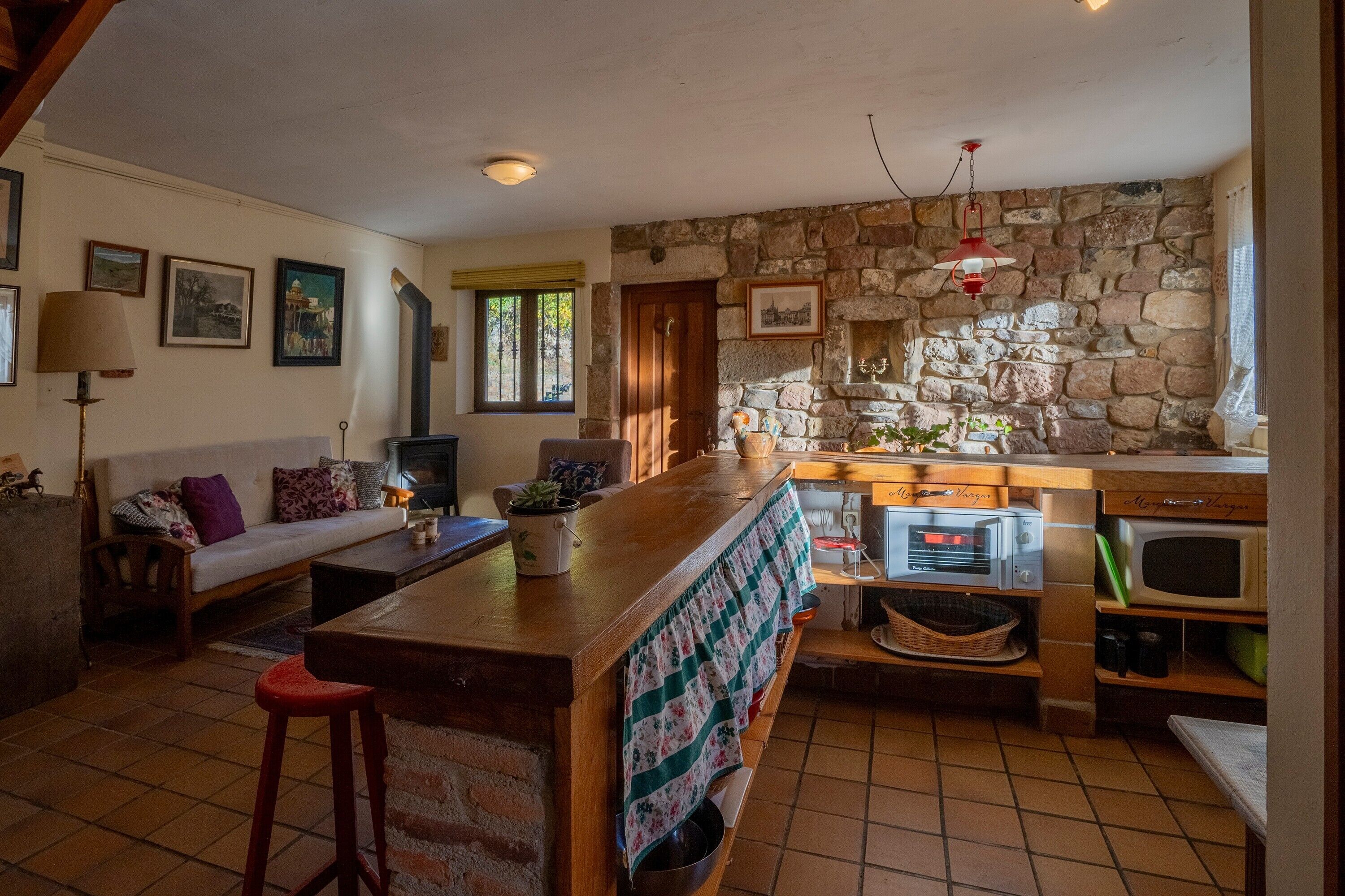 Een gezellige keuken met een stenen muur, een houten bar en retro apparaten.