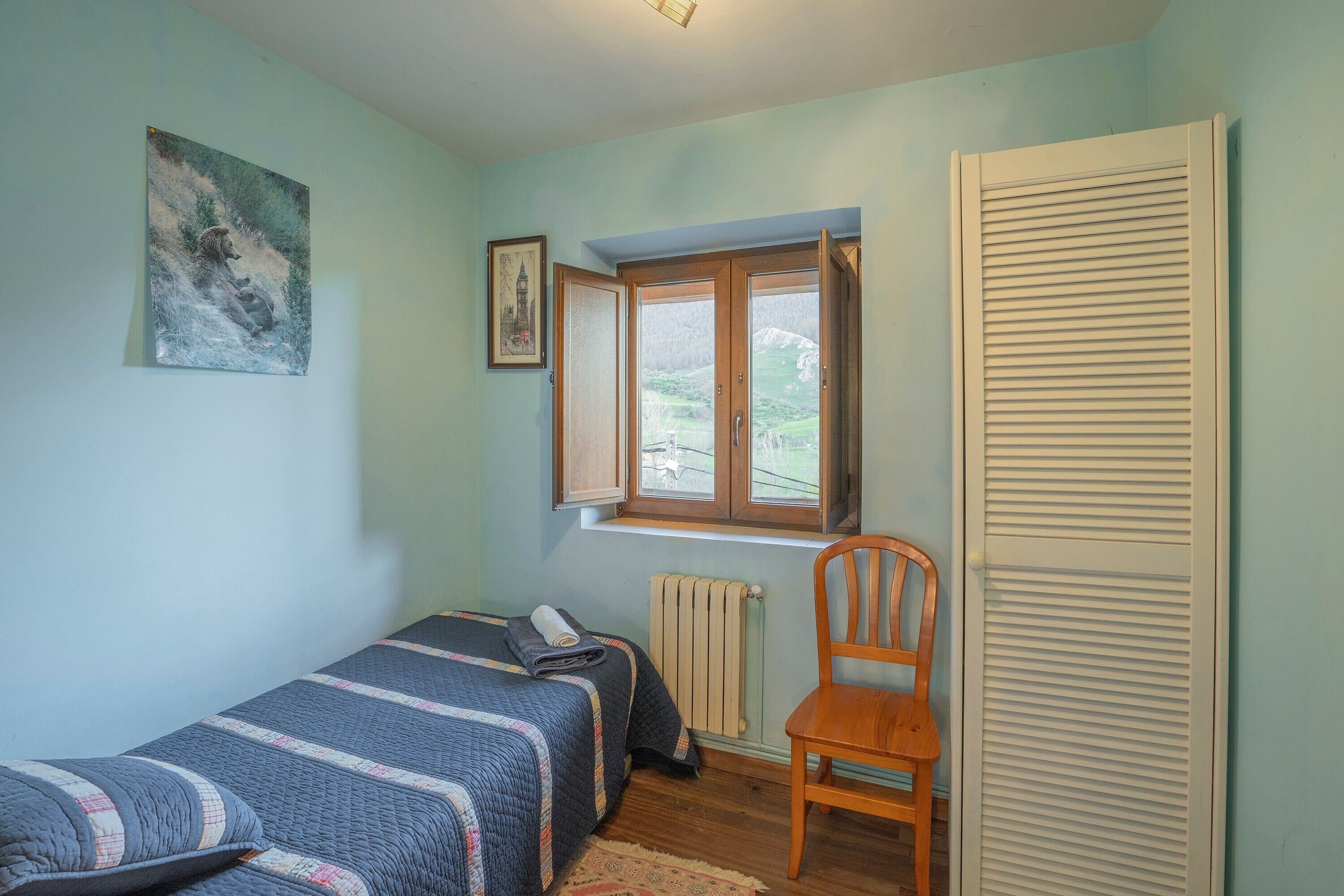 Ein Schlafzimmer mit einem Einzelbett, einem Sessel, einem Heizkörper und einem Fenster mit Blick.