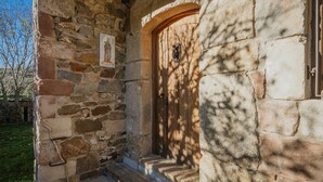 Edifici de pedra amb una porta de fusta i escales que condueixen a un porxo.