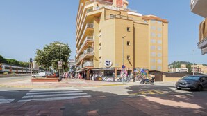 A multi-story building with balconies, a storefront with a sign, and a crosswalk.