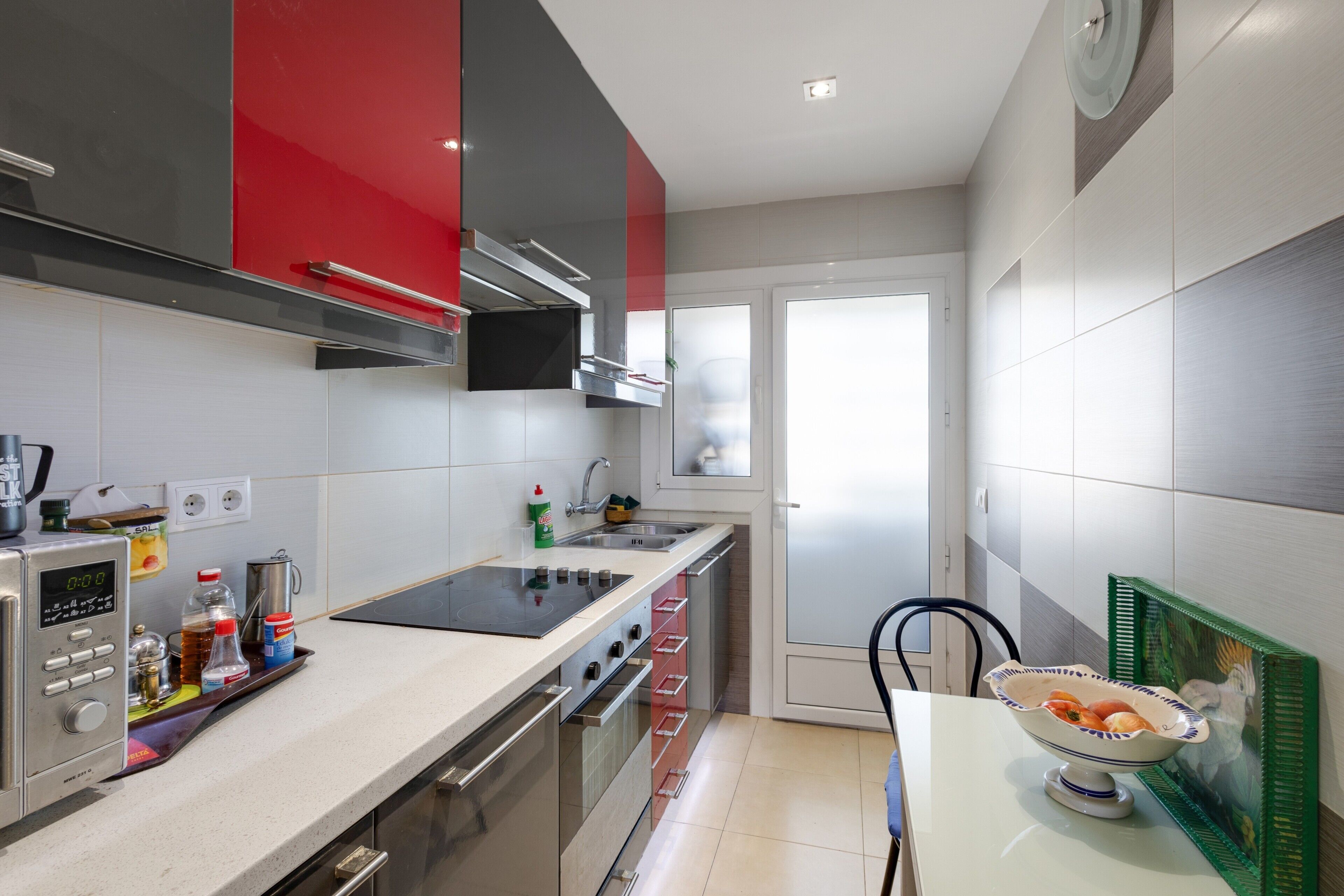 Een moderne keuken met roestvrijstalen apparatuur, een digitale klok en een schaal fruit op het aanrecht.