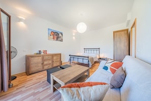 A bedroom with a bed, bedside table, wooden dresser, and a painting on the wall.
