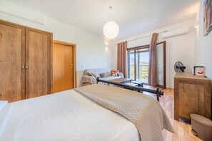 A bedroom with a bed, wooden wardrobe, bedside table, and a window with curtains.