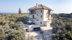 A multi-story house with a balcony, a garage, and a patio area. - Melissa apartment - stunning sea views, large garden and parking (Korfu)