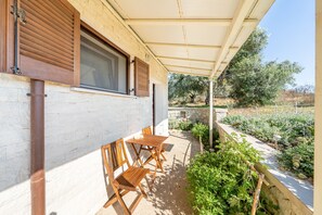Un patio cubierto con muebles de madera, un muro de piedra y un jardín.