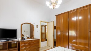 A bedroom with a bed, dresser, television, and wardrobe. - Sartiglia Domu, oasis of relaxation in the heart of Oristano with terrace and Wi-Fi (Oristano)